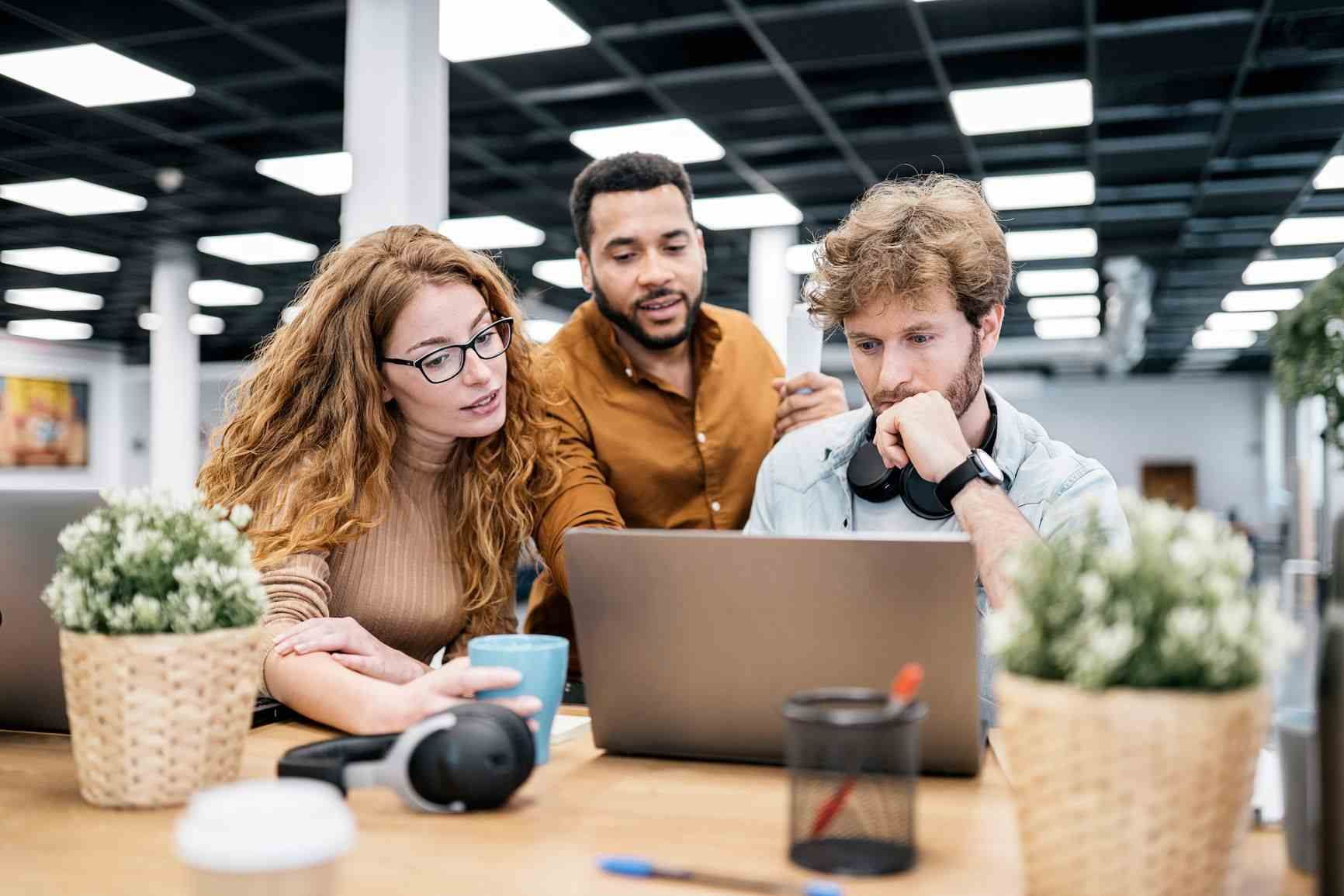 Three office workers looking at computer, trying to solve for recruiting bottlenecks